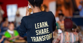 Woman wearing a T-shirt with the words, learn, share, transform on the back