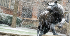 Sculpture of the Pitt panther in falling snow near the William Pitt Union